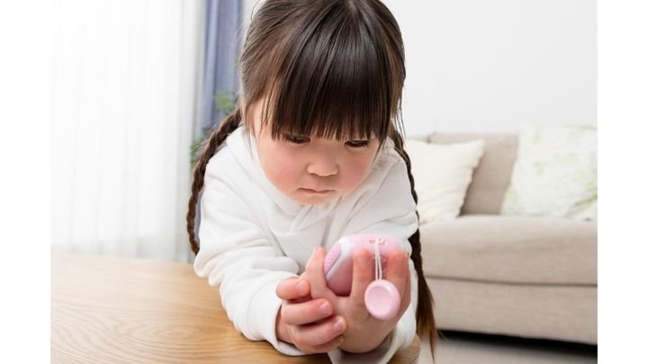 室内で真剣な表情でピンクのキッズ端末を見る女の子