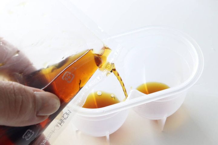 味玉名人の容器にめんつゆを注ぎ入れている手元