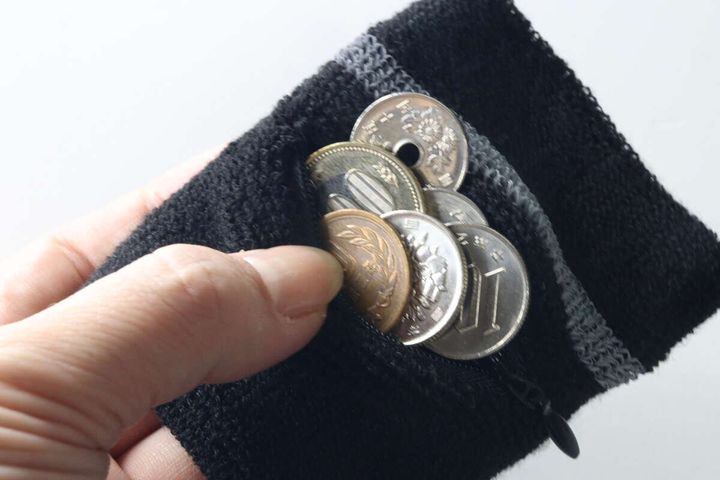 黒いリストバンドのファスナーポケットに小銭が数枚入っている