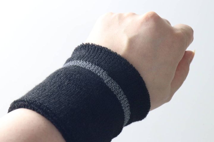女性の手首に黒いリストバンドを装着しフィット感を見せている