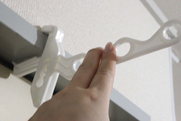 窓枠にダイソーのハンガーラック窓枠用を設置している手元