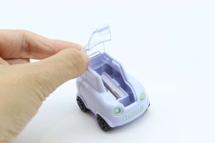 右手で車型鉛筆削りのボンネット部分を開けている