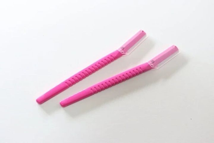 ピンク色のフェイス用カミソリ2本がキャップを付けた状態で白い背景に置かれている