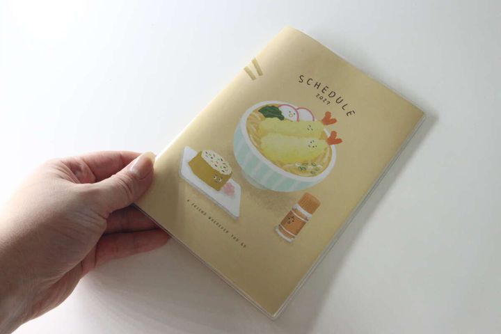 女性の手がセリアのダイアリーを手に持ちサイズ感を示している
