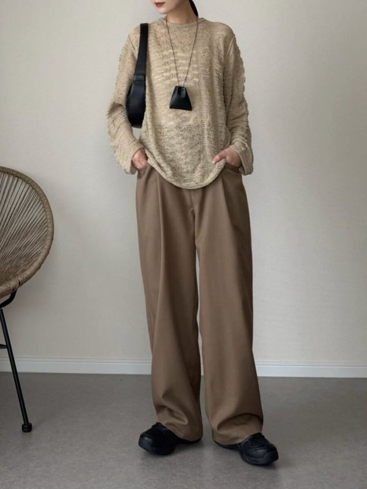 ベージュ透け感ニットとブラウンワイドパンツの女性