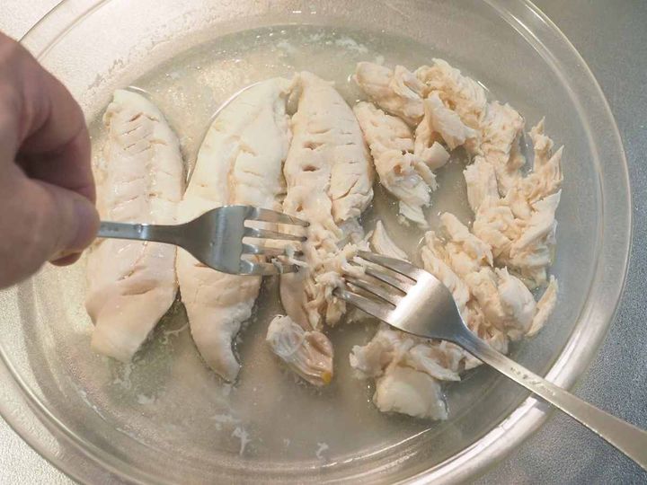 電子レンジで加熱した鶏ささみをフォークでほぐす様子