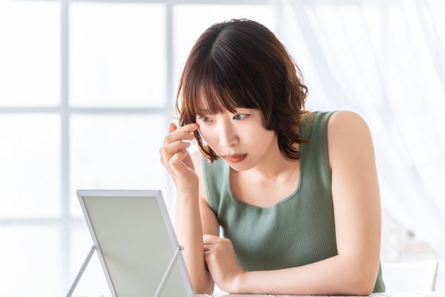 鏡で目元をチェックする女性