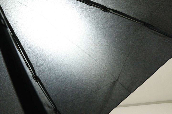 広げた黒い傘の生地をライトにかざし、光が透けて見える様子