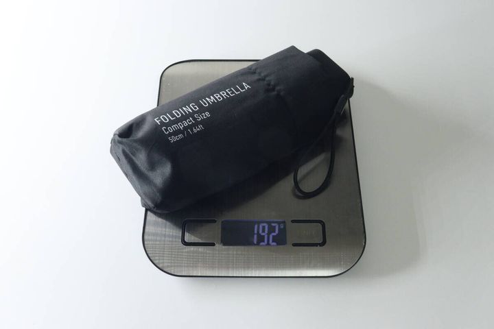 黒い折りたたみ傘をキッチンスケールに乗せ、192gと表示された重さを測っている