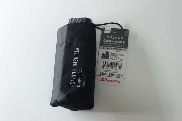 黒い折りたたみ傘がパッケージに入っており、商品名と770円の価格が見える