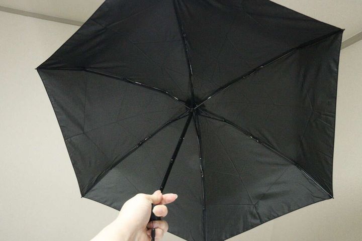 広げた状態の黒い折りたたみ傘を、下から見上げるように撮影している