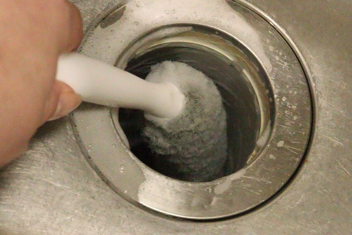 排水バスケットクリーナーでキッチンの排水口のワントラップ内部を泡立てながら掃除している様子