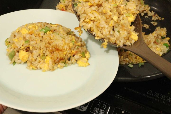 フライパンから「チャーハンこれ1本」を使って、出来上がったチャーハンを皿に盛り付けている