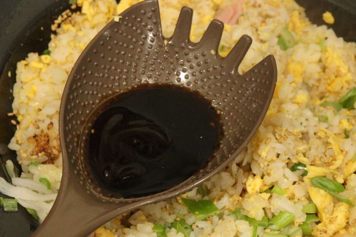 フライパンのチャーハンに「チャーハンこれ1本」のくぼみで醤油などの調味料を注いでいる