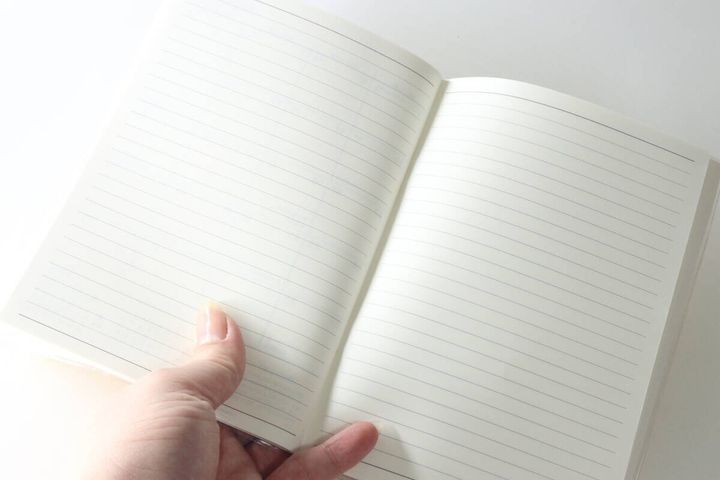 指で開かれた罫線入りのメモページ