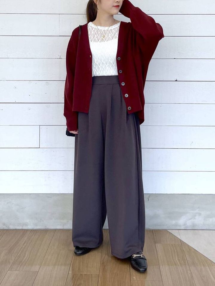 ボルドーのVネックカーディガンとワイドパンツを着用した女性