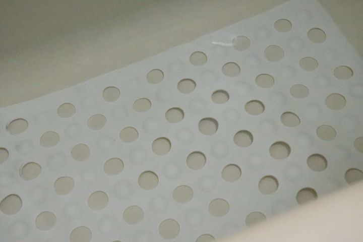 浴槽の底に敷かれた白い吸盤付浴槽マットのアップ。水に浸かっている