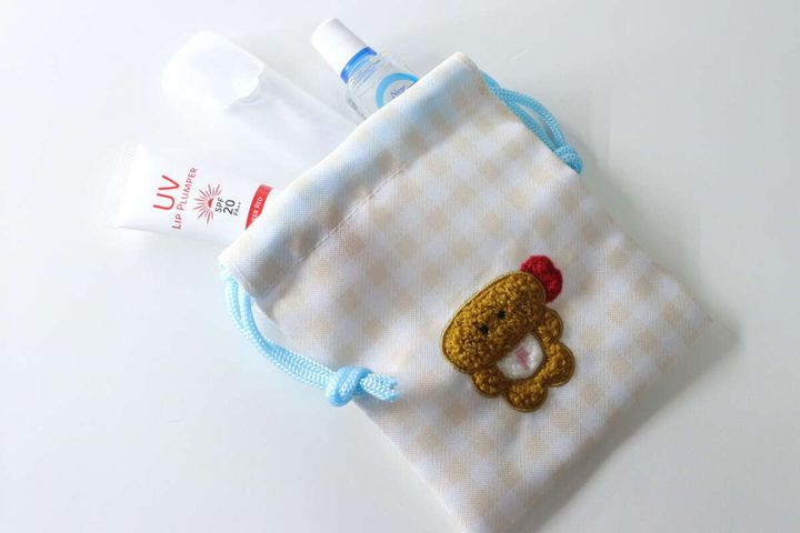 ダイソーのサガラ刺繍プチ巾着に目薬、リップ、デンタルピックを入れた状態