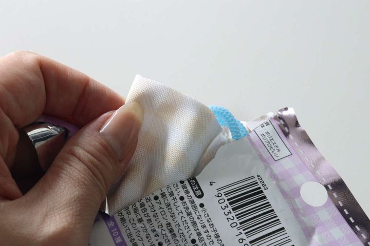 女性の手がダイソーのサガラ刺繍プチ巾着をパッケージから取り出している様子