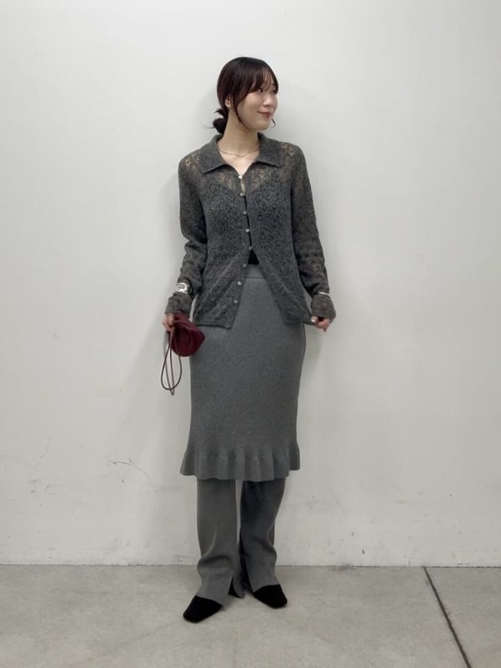透け感のあるグレーのポロニットとフリルスカートを着用し赤いバッグを持つ女性