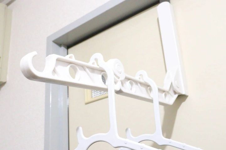 ドアに設置された物干しラックに白いハンガーを掛けている