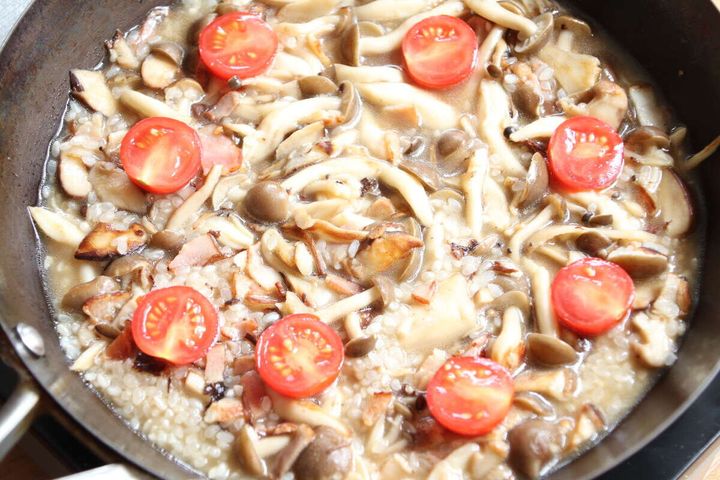 フライパンに米と水、ミニトマトが加えられ煮立っている調理中の様子