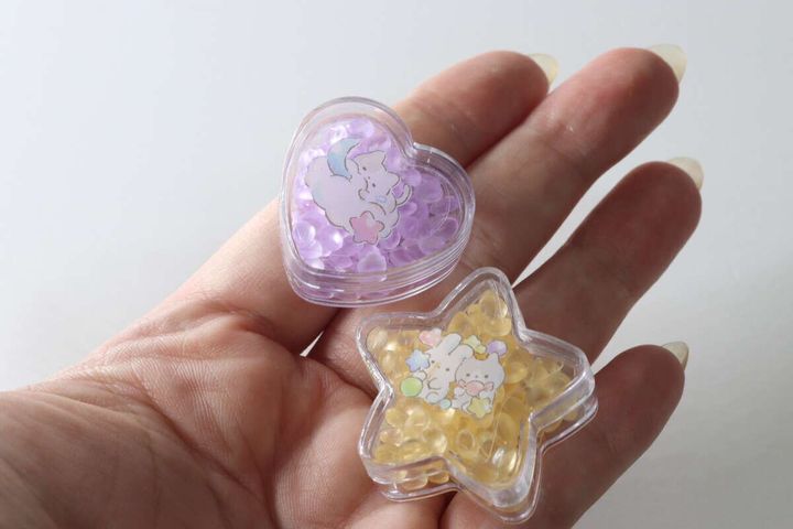 手のひらに乗せられた、紫色のハート型と黄色の星型の香り玉。