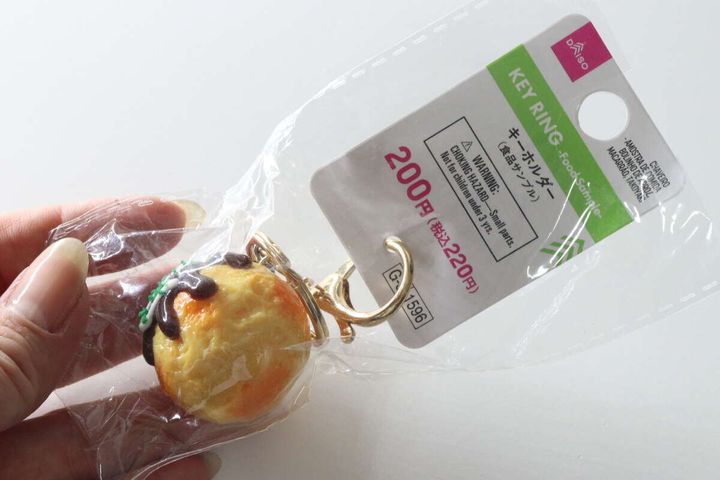 女性の手がダイソーのたこ焼きキーホルダーのパッケージを手に持っている