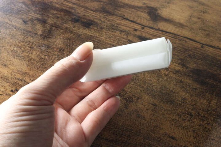 女性の手のひらに乗せられた個包装のミニウェットティッシュ