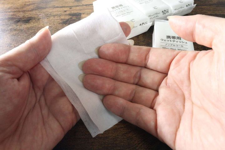 広げたウェットティッシュで手のひらを拭いている女性の手元