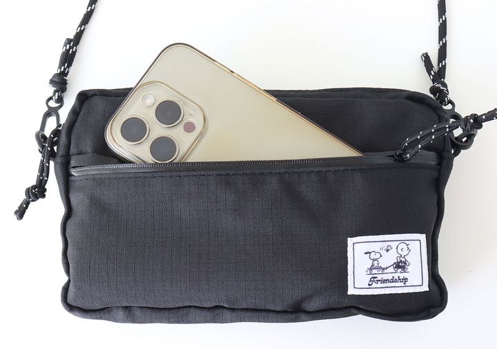 黒いショルダーバッグの前面ポケットにスマートフォンが入っている