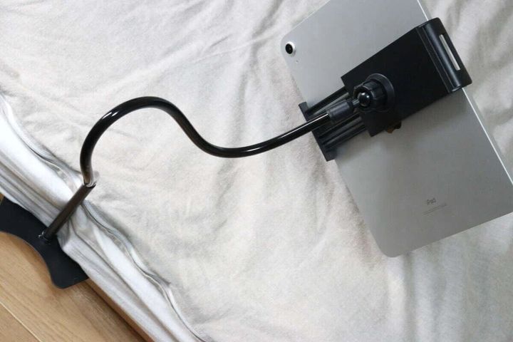 ベッドのマットレスとフレームの隙間に差し込まれたタブレットスタンドにiPadが固定されている