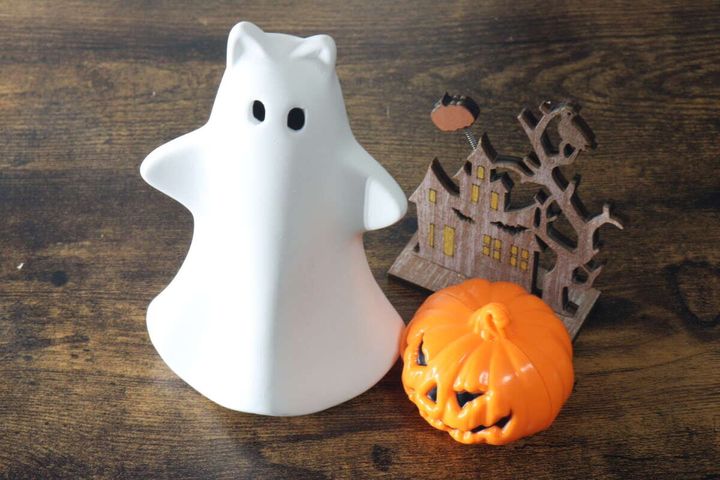 白いゴーストオブジェとパンプキン型LEDライト、木のハロウィン飾りが並べられている