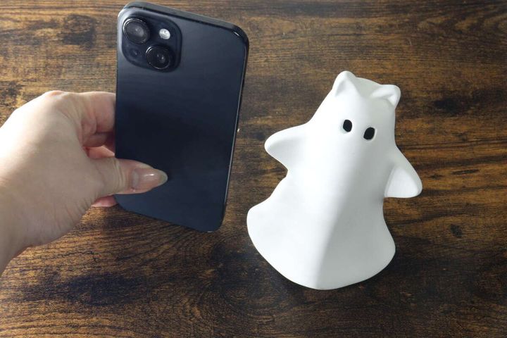 白いゴーストオブジェの横にスマートフォンを置いてサイズを比較している