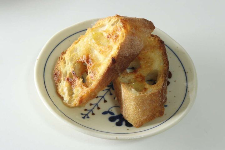 白い皿に盛り付けられた、焼き色のついたハニーガーリックフレーバートースト2切れ