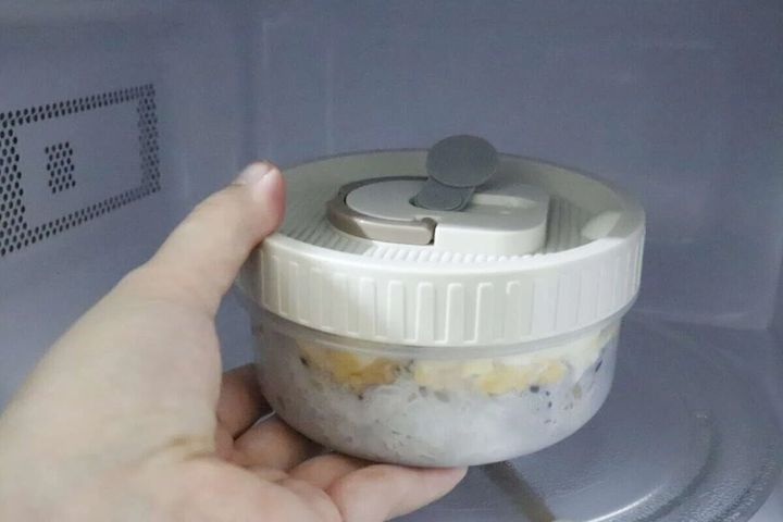 電子レンジ内で丸い弁当箱のエア弁を開ける手元