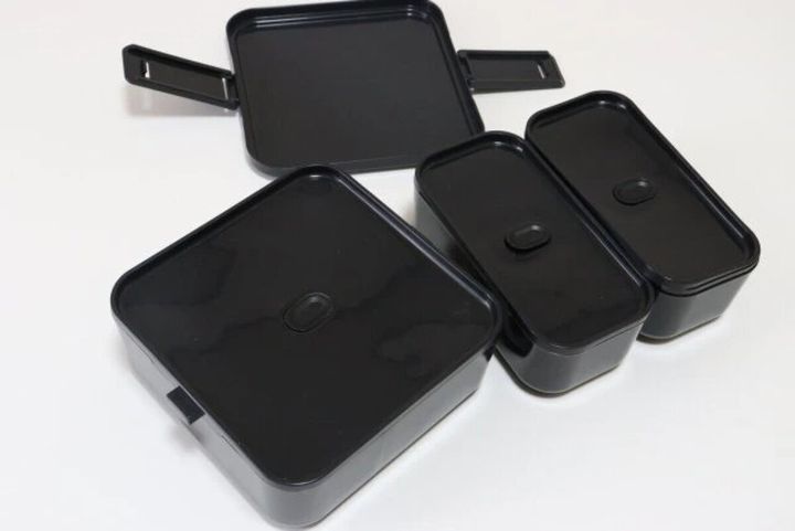 分解された黒い三分割弁当箱のパーツが並ぶ