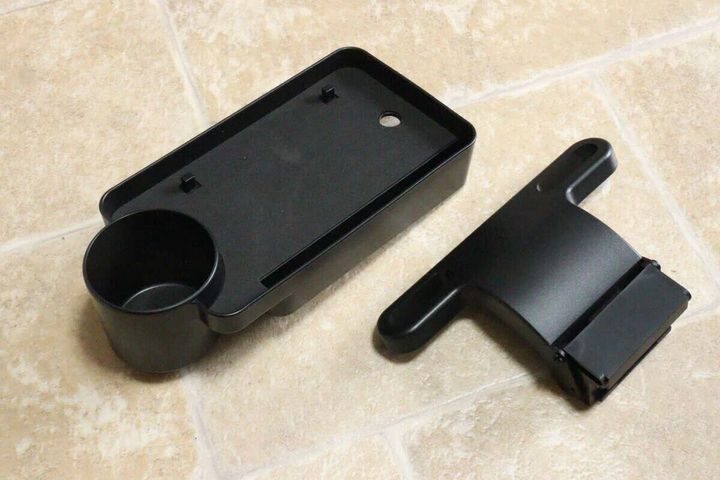 黒い車用トレイとヘッドレスト固定パーツが床に置かれている