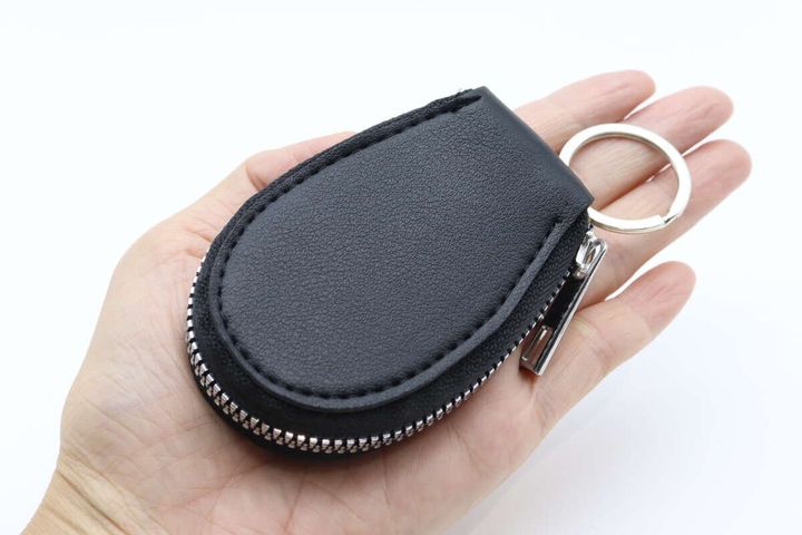 手のひらに黒い楕円形のキーケースが収まっている状態