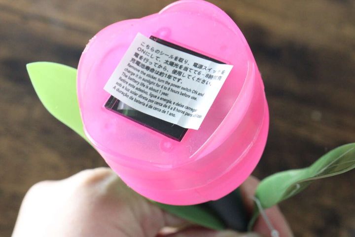 ピンクの花型ソーラーライトの裏側にあるソーラーパネルと、充電に関する注意書きシール
