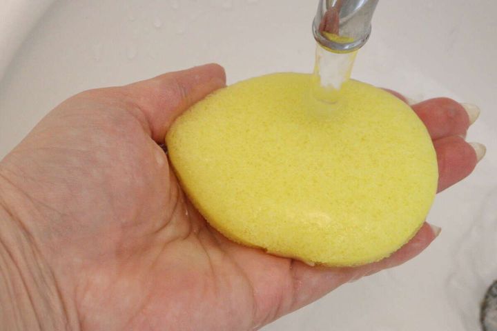 手のひらに乗せた黄色い洗顔パフに蛇口から水をかけている様子