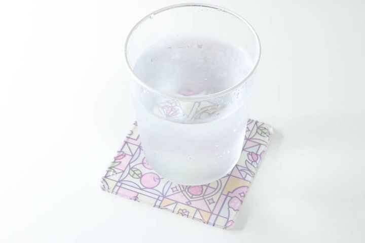 ステンドグラス風のアクリルコースターの上に水が入ったガラスのコップが置かれている