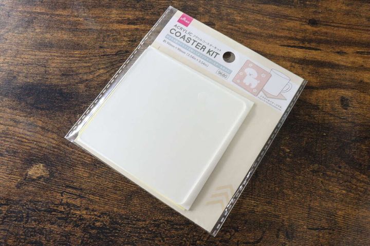 ダイソーのアクリルコースターキットのパッケージが木目のテーブルに斜めに置かれている