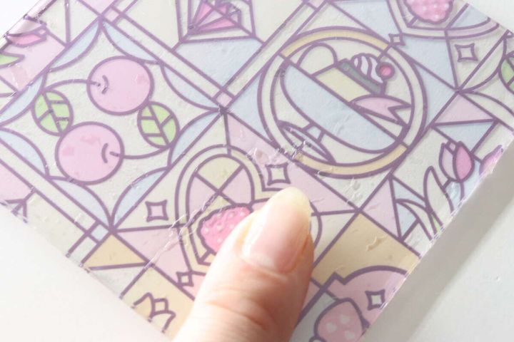 完成したアクリルコースターの表面にできた気泡を指で示している