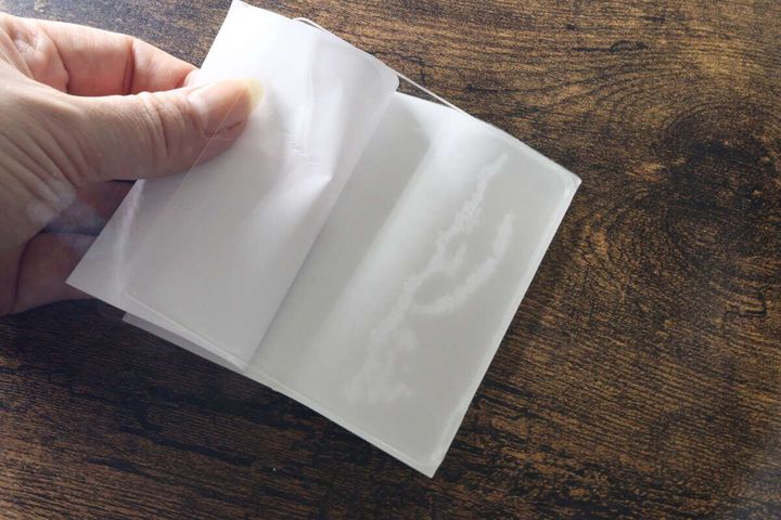 透明な粘着シートの剥離紙を剥がしている指先