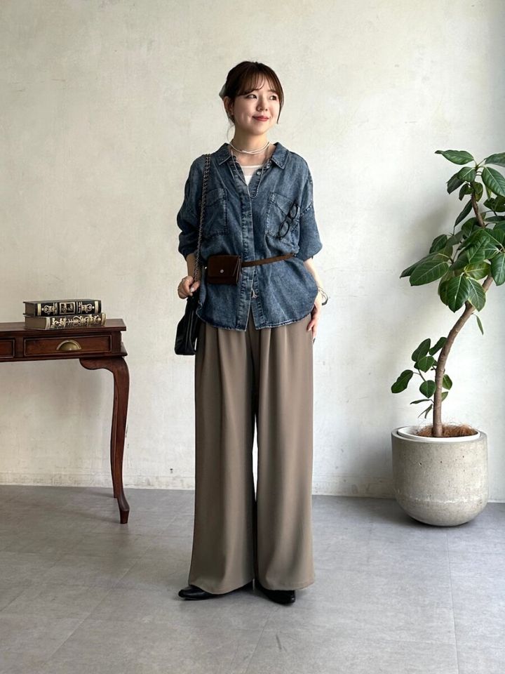 デニムシャツに細ベルトでウエストマークし、ブラウンワイドパンツを合わせた女性