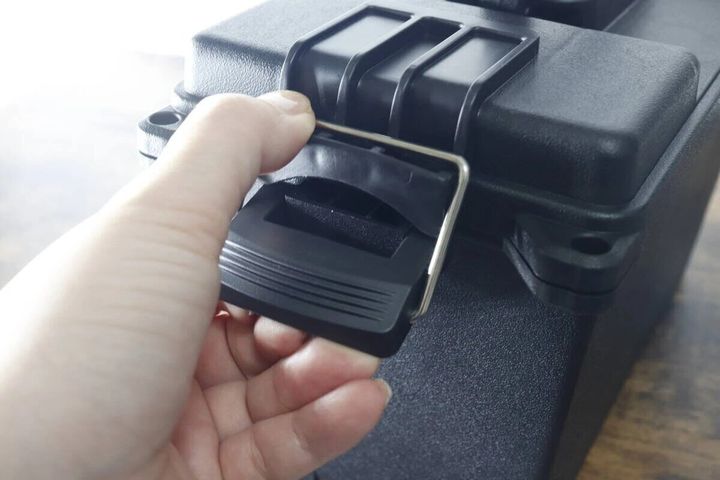 手が黒い防滴工具箱のバックルを開けようとしている