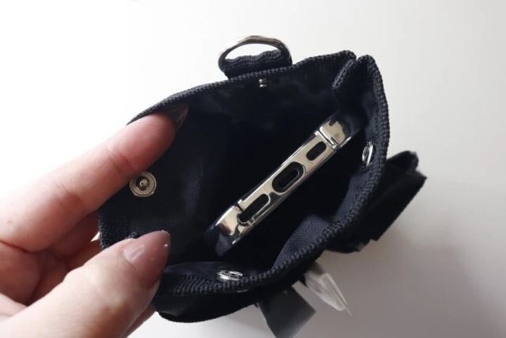 手が黒いツールポーチのメイン収納にスマホを入れている