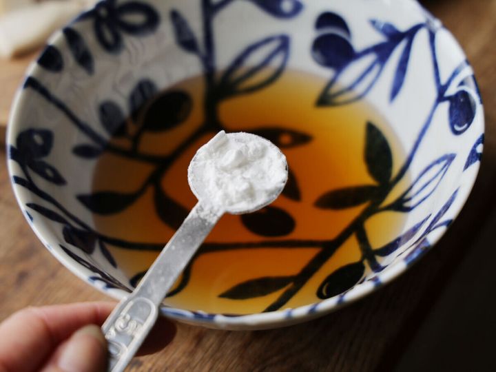 青い模様の器に入っためんつゆと水に、小さじスプーンで片栗粉が加えられている様子