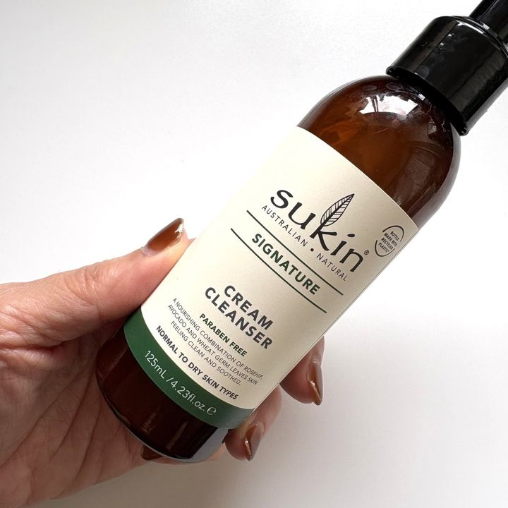 手に持ったSukin（スーキン）のクリームクレンザーのボトル